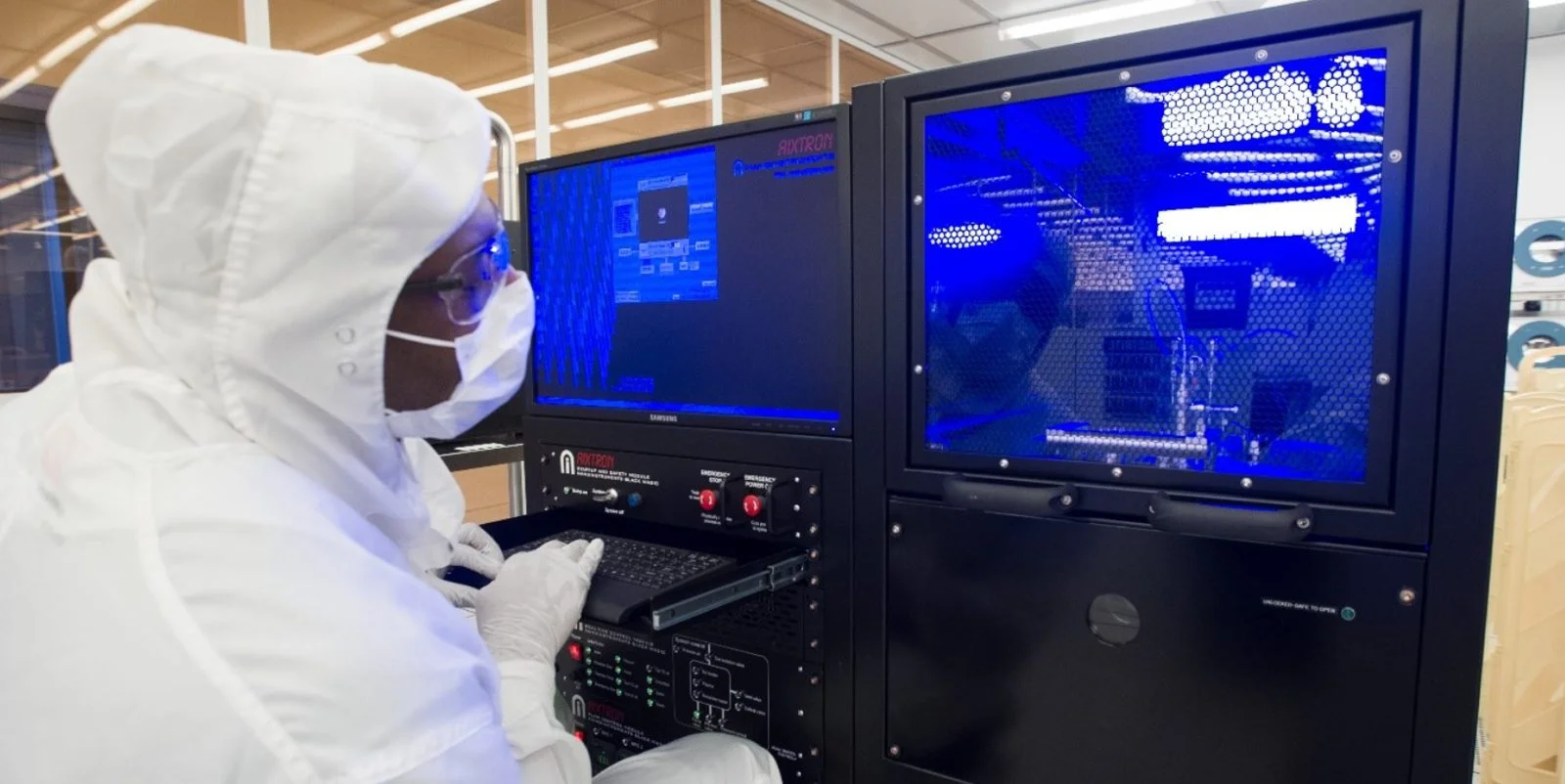 Researchers examining semiconductor fabrication equipment in a cleanroom